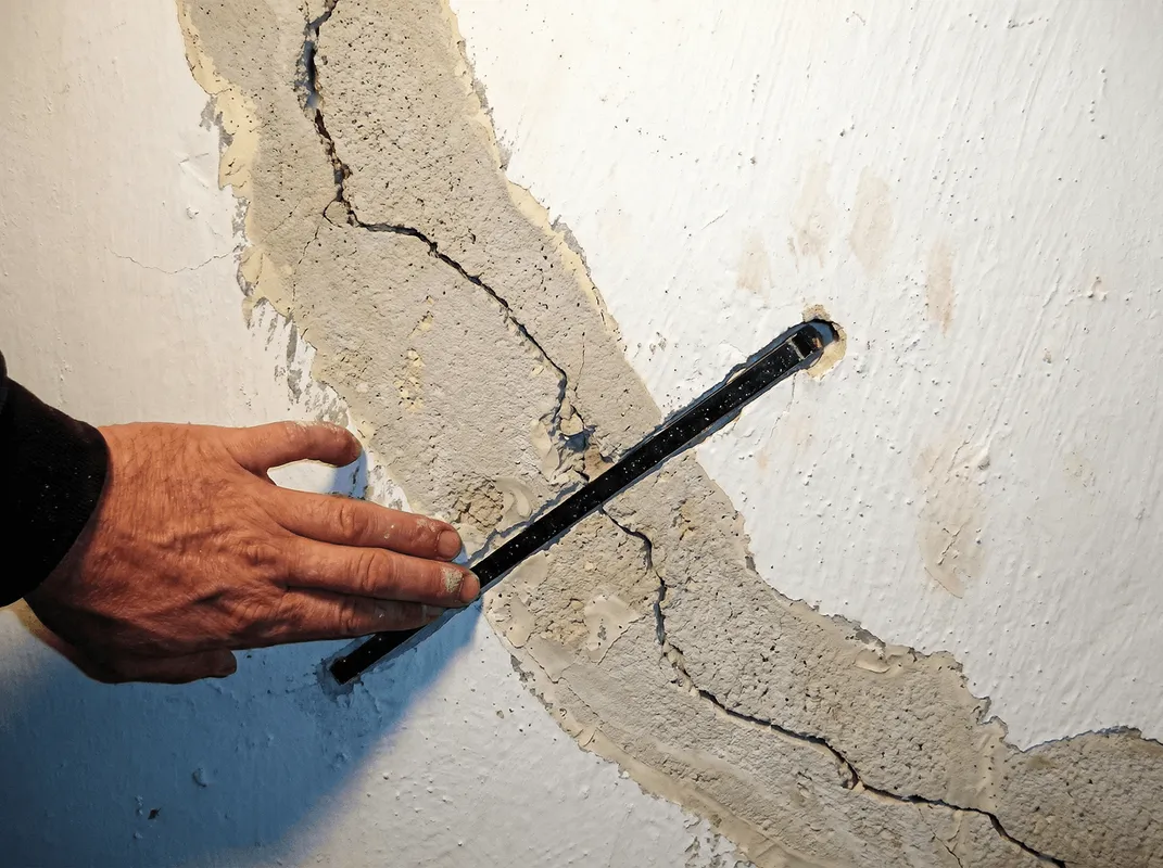 A wall with a large crack is being inspected by a professional in Bellevue, WA